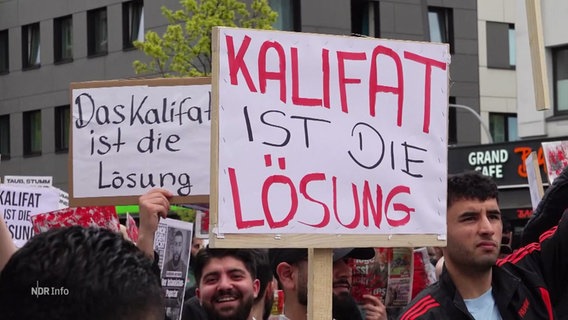Nahaufnahme von einem Schild, das auf einer Demo hochgehalten wird. Darauf steht "Kalifat ist die Lsöung". © Screenshot 