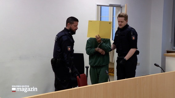 Zwei Justizbeamte führen einen Angeklagten in einen Gerichtssaal am Lübecker Landgericht. © NDR 