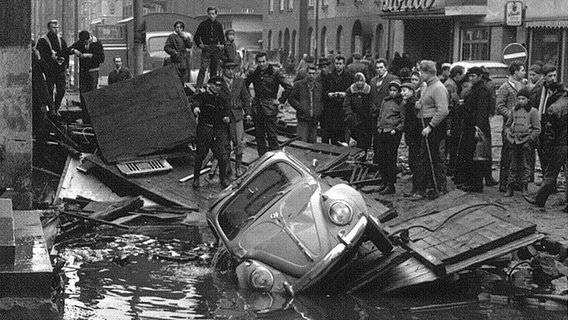 Menschen schauen bei der Bergung eines VW Käfer zu nach der Sturmflut 1962 in Hamburg-Wilhelmsburg. © NDR Foto: Günther Hachmeister