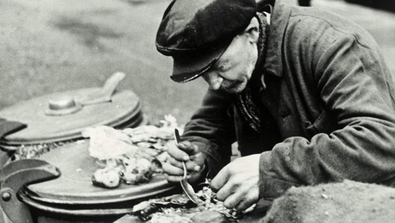 Ein alter Mann nimmt 1946 an einer Mülltonne eine Mahlzeit ein. © picture alliance / akg-images Foto: Ursula Litzmann