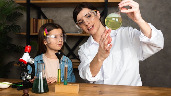 Eine Frau zeigt einem Mädchen ein wissenschaftliches Experiment. © picture alliance / Zoonar | Oleksandr Latkun 