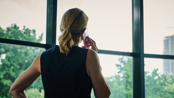 Eine Frau steht in einem Büro am Fenster und telefoniert. © picture alliance/dpa | Annette Riedl Foto: Annette Riedl