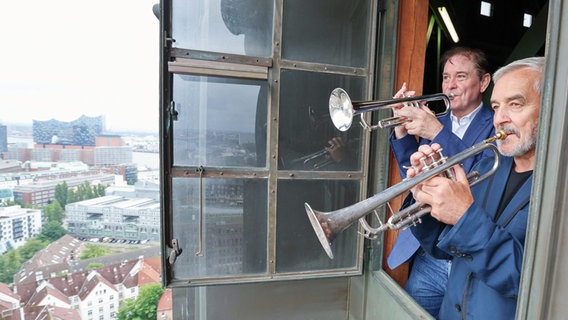Die Hamburger Turmbläser Horst Huhn (r) und Josef Thöne stehen mit ihren Trompeten bei einem Fototermin an einem Fenster im Turm der Hauptkirche St. Michaelis. © picture alliance/dpa Foto: Christian Charisius