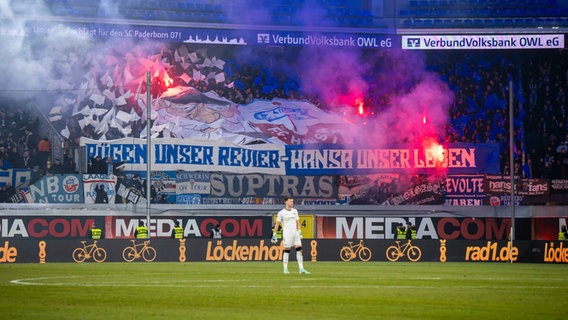 Hansa Rostock-Fans stehen in einer Fan-Kurve und haben Bengalos gezündet - Rauch steigt auf. © NDR 