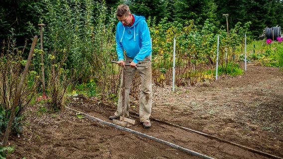 Peter Rasch verdichtet die Erde in einem neu angelegten Gartenweg © NDR Foto: Udo Tanske