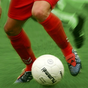 Fußballer mit roten Stutzen im Begriff den Ball zu spielen © panthermedia / Klosko Foto: Robert Klosko