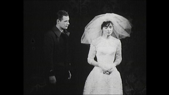 Eine Braut mit Sonnenschirm und ein Bräutigam im Theaterstück Heinrich V. auf der Bühne (1964, Bremen)  