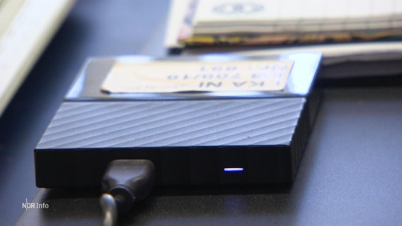 Eine Festplatte liegt auf einem Schreibtisch und ist mit einem Post-it versehen. © Screenshot 