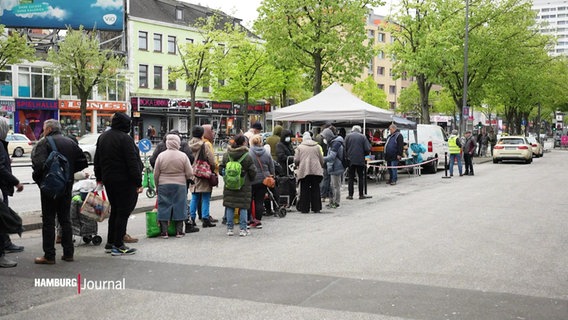 Viele Menschen stehen in einer Schlange auf der Hamburger Reeperbahn vor einer Essensausgabe an einem Zelt. © Screenshot 