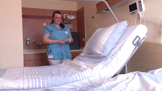 Eine Pflegkraft hält die Fernbedienung eines Krankenbetts. © Screenshot 