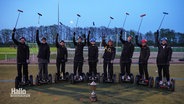 Die "Lions" aus der Wedemark - das Weltmeister-Team im Segway-Polo steht auf ihren Geräten im Halbkreis um einen Pokal, die Schläger erhoben. © Screenshot 