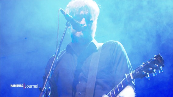 Der Sänger der Band Kettcar steht mit seiner Gitarre auf der Bühne. © Screenshot 