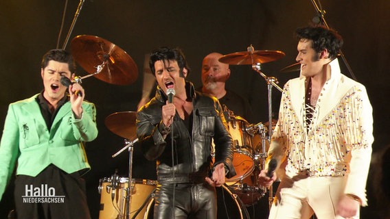 Dre Elvis Tribute Artists stehen gemeinsam auf einer Bühne. © Screenshot 
