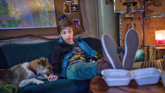 Till (Otto von Grevenmoor) sitz mit seinem Hund „Socke“ auf einem Sofa. © NDR/Studio HH Foto: Boris Laewen
