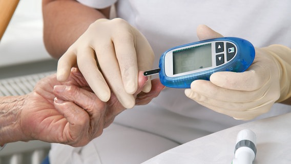 Eine Frau mit Gummihandschuhen testet eine ältere Dame mit einem Diabetesmessgerät © Colourbox Foto: PetraD
