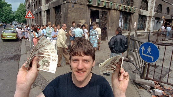 Ein junger Mann freut sich am 1. Juli 1990 über seine D-Mark-Banknoten. © dpa / picture-alliance Foto: Kai-Uwe Wärner