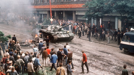 Niederschlagung "Prager Frühlings": Eine Menschenmenge umringt am 21. August 1968, dem ersten Tag der Besetzung, in der Prager Innenstadt einen russischen Panzer, der neben einem ausgebrannten Fahrzeug zum Stehen gekommen ist. © picture-alliance / dpa Foto: Tewes