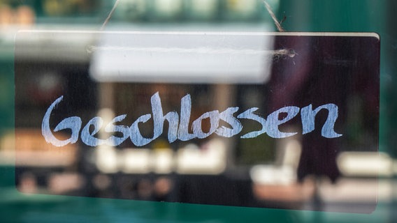 Ein Schild mit dem Wort "geschlossen" hängt hinter einer Glastür. © photocase Foto: axelbueckert