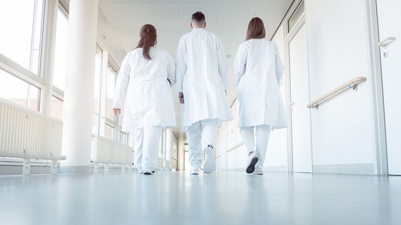 Zwei Ärztinnen und ein Arzt gehen auf einem Krankenhausflur entlang © panthermedia Foto: Kzenon
