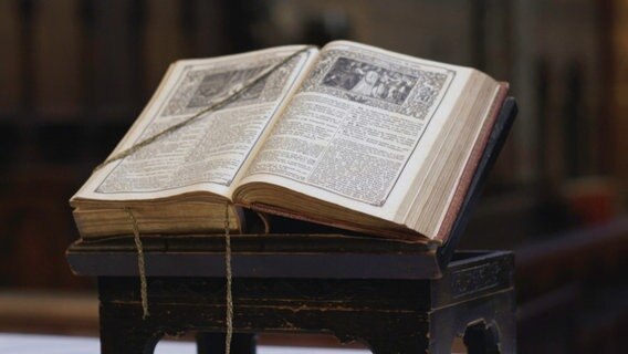Aufgeschlagenen Bibel liegt auf einem Podest © ZDF / RMCProduction 