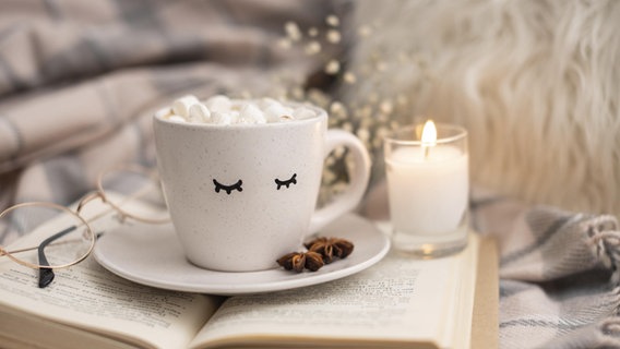 Ein Latte Macchiato, eine Brille und eine Kerze liegen auf einem Buch © picture alliance / Zoonar | Oleksandr Latkun 