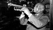 Der Vater des "St. Louis Blues", Trompeter W.C. Handy, sitzt vor einem offenen Fenster und spielt Trompete © picture alliance / ASSOCIATED PRESS 