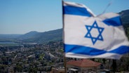 Blick auf die israelische Stadt Kiryat Shmona. Im Vordergrund weht die israelische Flagge. © picture alliance / AP Foto: Ariel Schalit
