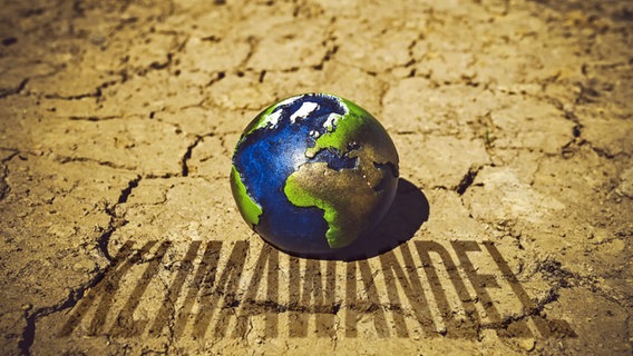 Eine Erdkugel auf ausgetrocknetem Boden mit dem Schriftzug Klimawandel (Symbolbild) © picture alliance / CHROMORANGE | Christian Ohde 
