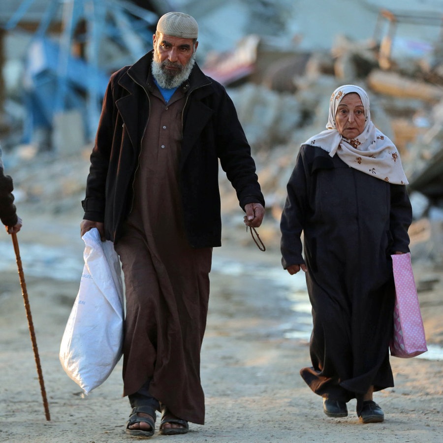 Menschen gehen an zerstörten Gebäuden im Flüchtlingslager Al-Maghazi im Zentrum des Gazastreifens im Zentrum des Gazastreifens vorbei. © dpa Foto: XinHua