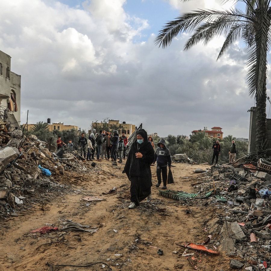 Palästinenser gehen durch die Überreste zerstörter Gebäude nach israelischem Bombardement in Rafah (Süd-Gaza). © dpa Foto: Abed Rahim Khatib