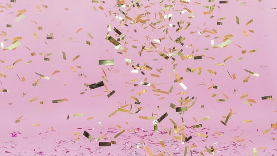 Glänzendes goldenes Konfetti fällt herab auf einem rosa Hintergrund © Zoonar Foto: Oleksandr Latkun