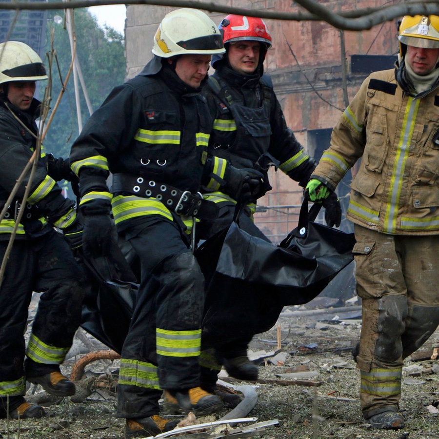 Auf diesem vom Staatlichen Katastrophenschutz der Ukraine zur Verfügung gestellten Foto tragen Feuerwehrleute eine Leiche nach einem, nach ukrainischen Angaben, russischen Luftangriff. © State Emergency Service of Ukrai/AP/dpa 