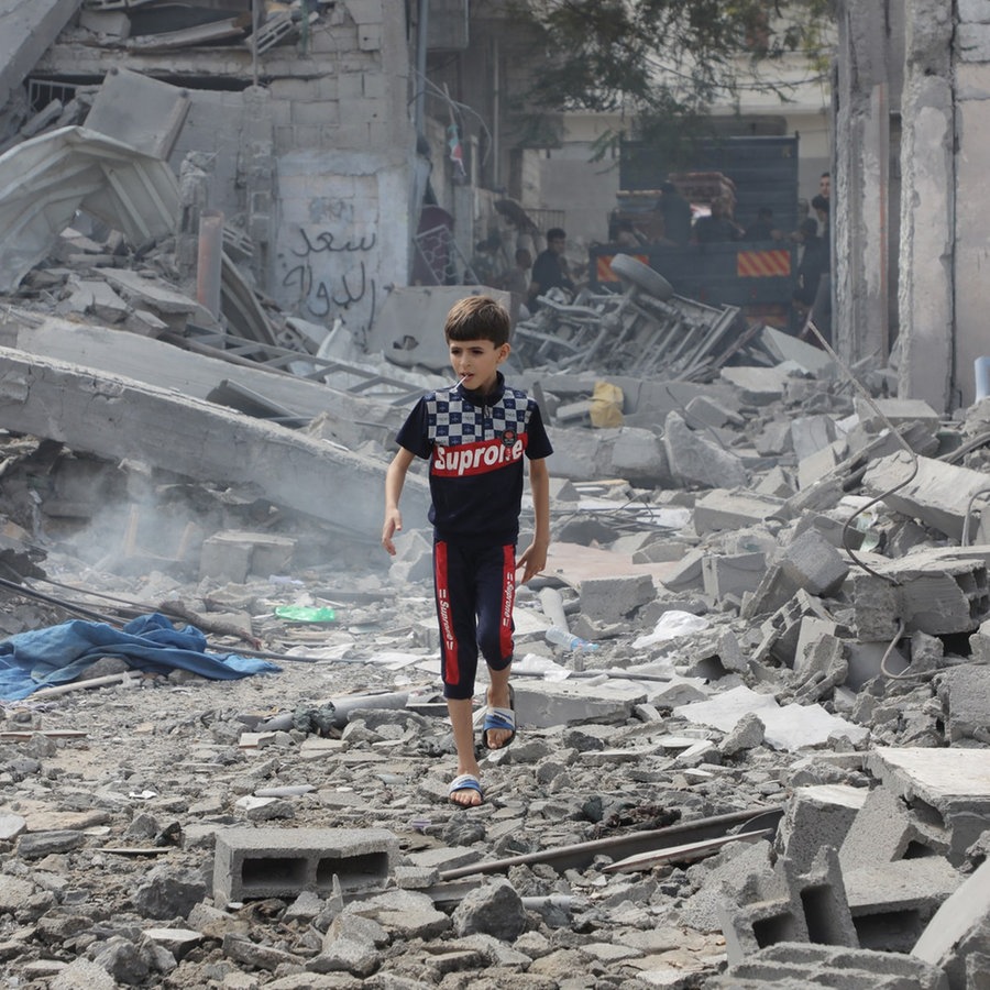 Palästinensische Gebiete, Flüchtlingslager Bureij: Ein palästinensisches Kind steht nach den israelischen Luftangriffen auf Überresten zerstörter Gebäude. © picture alliance / ZUMAPRESS.com | Foto: Naaman Omar