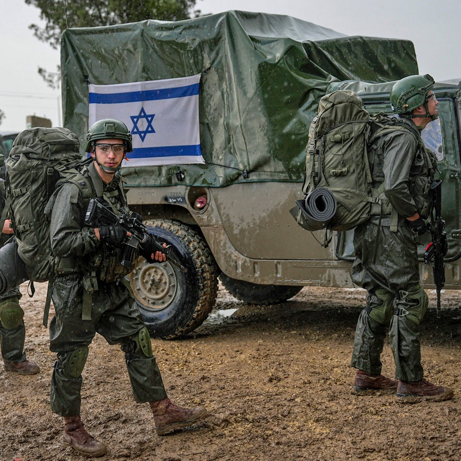 Israelische Soldaten stehen neben Militärfahrzeugen, während sie sich an einem Sammelpunkt nahe der Grenze zum Gazastreifen vorbereiten. © AP/dpa Foto: Ohad Zwigenberg