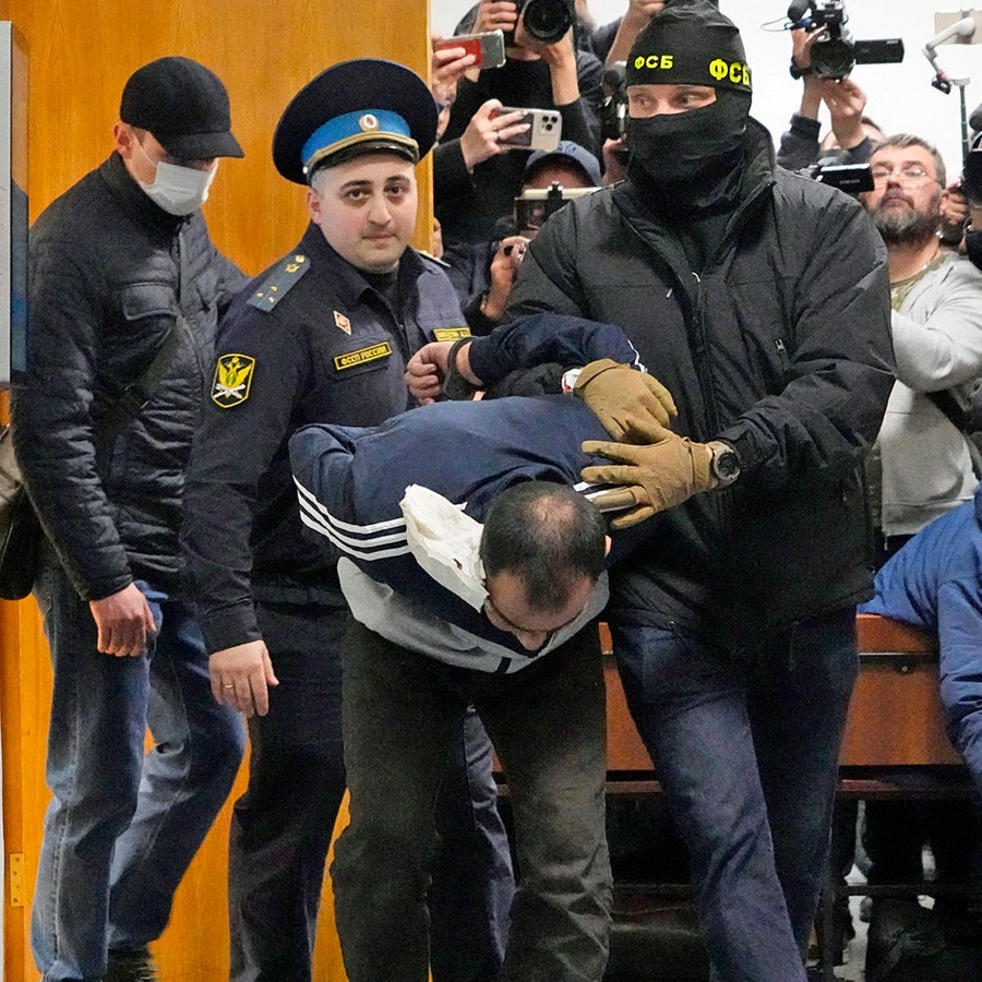 Ein Tatverdächtiger des Terroranschlags auf die Konzerthalle Crocus City Hall in Moskau wird von Polizisten und FSB-Beamten im Basmanny-Bezirksgericht eskortiert. © AP Foto: Alexander Zemlianichenko