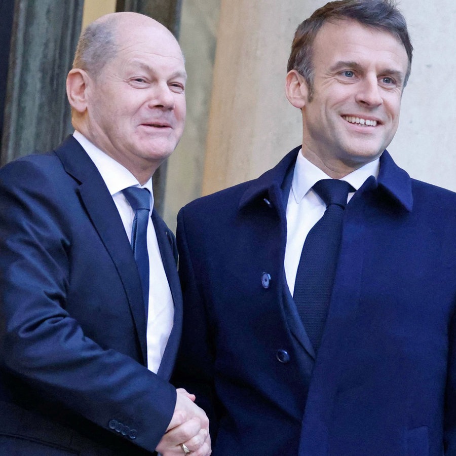 Der Präsident von Frankreich, Emmanuel Macron (Mitte), gibt Bundeskanzler Olaf Scholz (links) die Hand, als dieser im Elysee-Palast eintrifft. © AFP/dpa Foto: Ludovic Marin