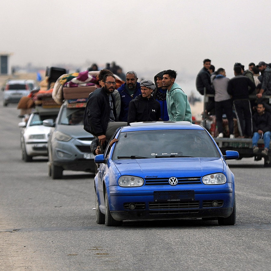 In Rafah im Gazastreifen fahren Menschen mit vollbeladenen und überfüllten Autos auf einer Straße, auch Fußgänger sind zu sehen. © XinHua/dpa Bildfunk Foto: Yasser Qudih