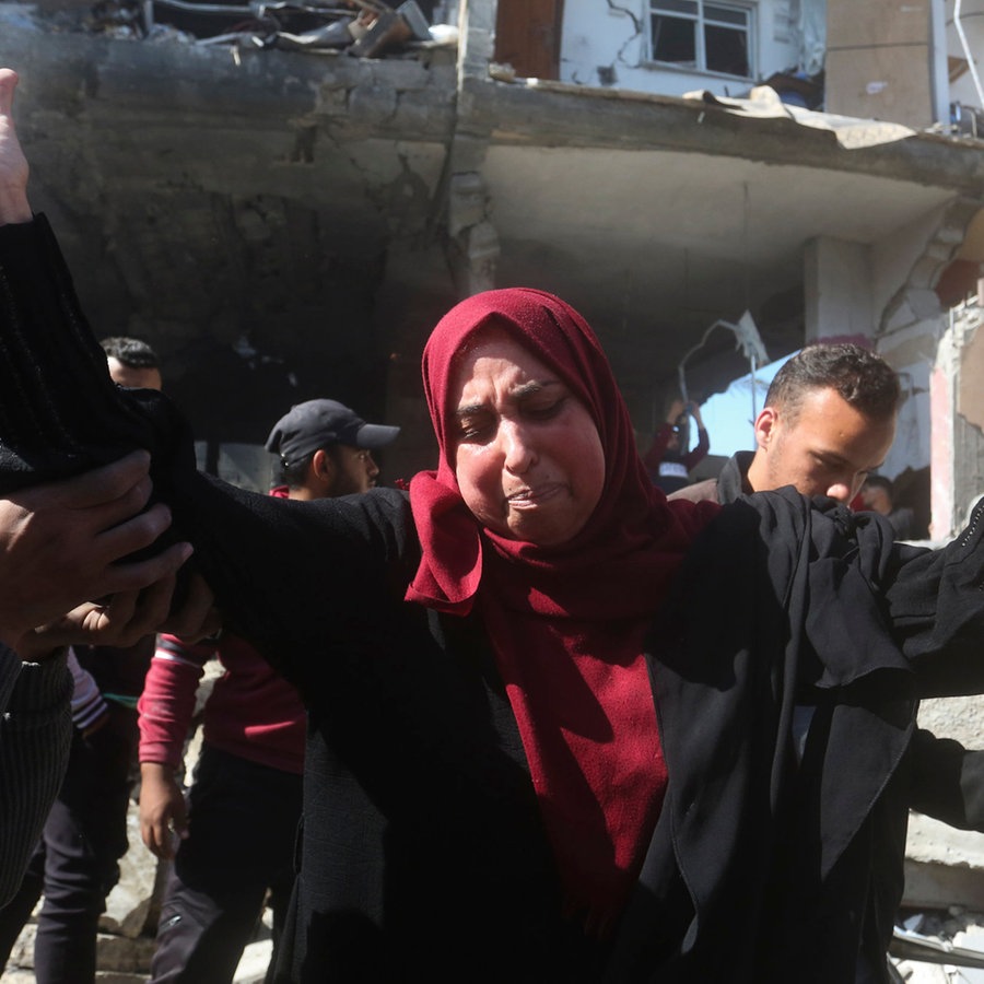 Eine Palästinenserin reißt verzweifelt vor zerbombten Gebäuden die Hände in die Höhe. © dpa bildfunk/AP Foto: Hatem Ali