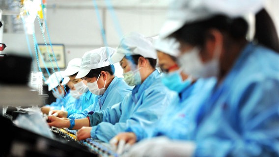 Arbeiter und Arbeiterinnen einer chinesischen Elektronikfabrik in Schutzkleidung. © dpa picture alliance Foto: Yu Fangping