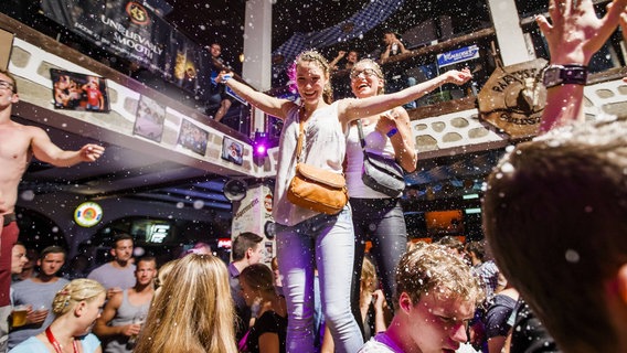 Junge Urlauber feiern in einer Disko. © IMAGO / Lars Berg 