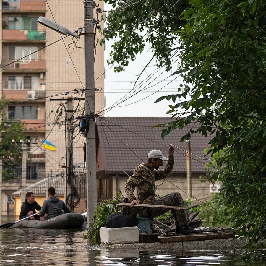 Ein Mann erreicht sein überflutetes Haus. Infolge des verheerenden Hochwassers nach der Zerstörung des Kachowka-Staudamms sind im russisch besetzten Teil des südukrainischen Gebiets Cherson mehrere Menschen ums Leben gekommen. © dpa-Bildfunk Foto: Evgeniy Maloletka/AP/dpa