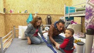 Eine Familie sitzt in einer Flüchtlingsunterkunft auf einem Bett. © NDR Foto: Nadia Yaqub