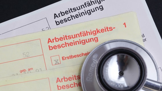 Eine Arbeitsunfaehigkeitsbescheinigung und ein Stethoskop. © picture alliance / Eibner-Pressefoto Foto: Fleig / Eibner-Pressefoto