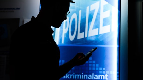 Ein Polizist steht mit einem Smartphone im Landeskriminalamt Niedersachsen (gestellte Szene). © picture alliance/dpa/Julian Stratenschulte Foto: Julian Stratenschulte