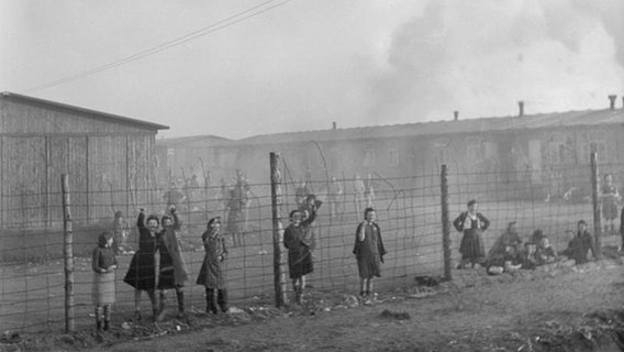 Menschen stehen an einem Zaun im Konzenrationslager Bergen-Belsen. © Imperial War Museum 