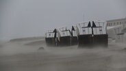 Der Sturm weht Sand über den Strand, auf dem mehrere Strandkörbe liegen. © dpa Bildfunk Photo: Peter Kuchenbuch-Hanken