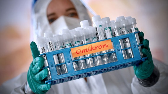 Eine Laborarbeiterin hält zahlreiche Omikron-Laborproben in die Kamera. © picture-allaince Foto: Sven Simon | Frank Hoermann