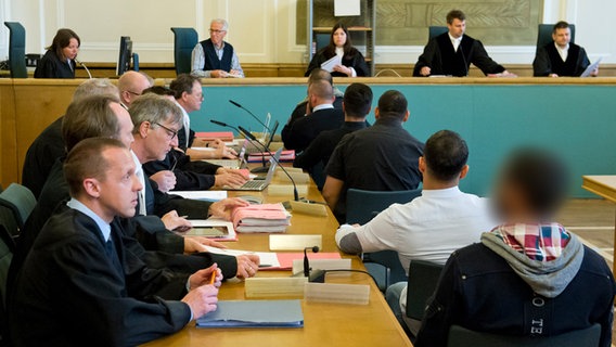 Sechs Angeklagte (r) sitzen im Landgericht Osnabrück hintereinander, ihnen gegenüber sitzen Anwälte, vorne die Kammer © dpa Bildfunk Foto: Philipp Hülsmann