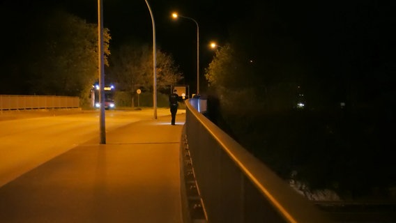 Ein Polizist geht im Dunkeln über eine Brücke. © Daniel Friederichs Foto: Daniel Friederichs