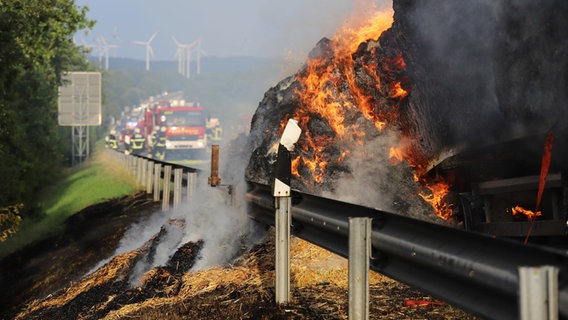 Stohballen auf einem Anhänger stehen auf einer Autobahn in Flammen und dahinter staut sich der Verkehr. © Westküstennews Foto: Westküstennews